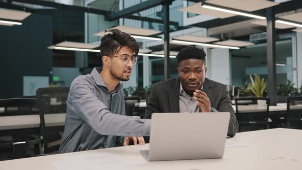 Two Multicultural Professional Male Coworkers Men Colleagues Sit at Office Use Laptop Discuss