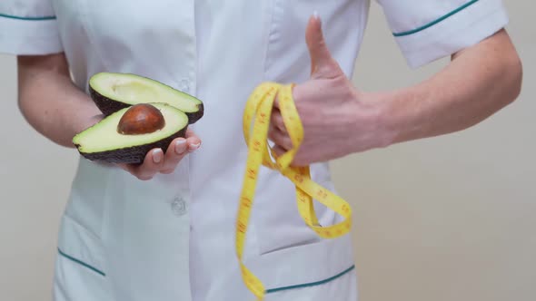 Nutritionist Doctor Healthy Lifestyle Concept - Holding Organic Avocado Fruit and Measuring Tape