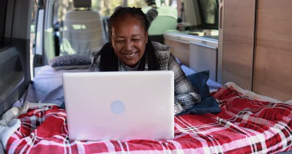 Mature african woman using computer laptop inside mini van camper