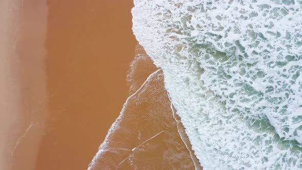 Aerial Drone Shot of Waves Breaking on Sandy Beach Shore, Vertical Top Down View from Above of Golde