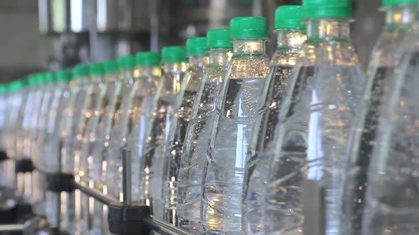 White Plastic Bottles Stand on the Water Bottling Line, Filled with Mineral Water, and Clogged with