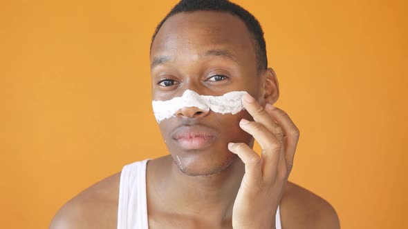 AfricanAmerican Man Applies Moisturizer To His Face Healthy Glowing Skin Isolated Yellow Background