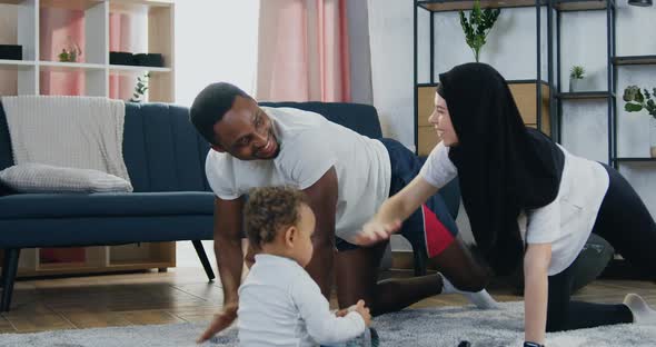 Couple Doing Stretching Exercises During Home Workout and their Cute Dark-Skinned Little Son