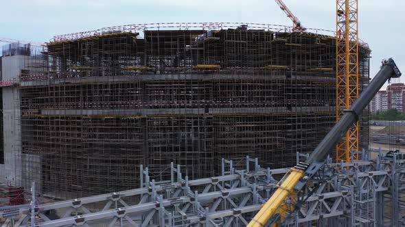 Stadium Building with Scaffolds and High Tower Cranes