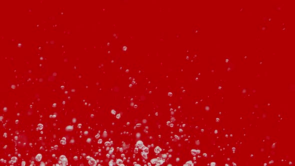 Multiple Drops of Water Fly Up and Spray in Different Directions on Red Background