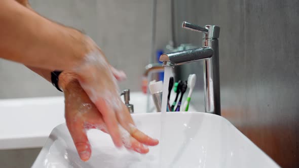 Person Rinsing Hands in Bathroom at Home. The Man Washes His Hands in the Bathroom. 