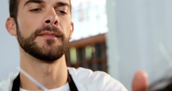 Male hairdresser cutting a womans hair with scissor