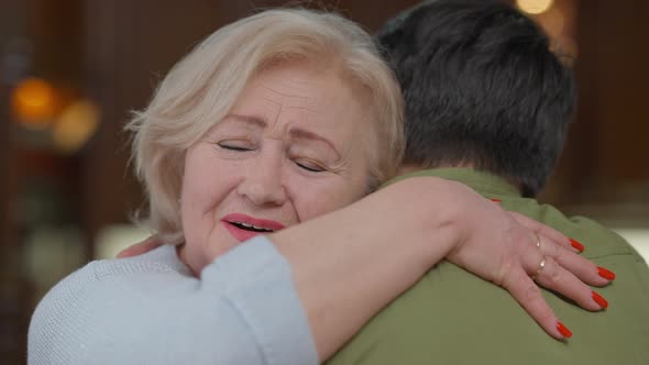 Closeup of Happy Surprised Senior Woman Looking at Camera with Excited Facial Expression Hugging Man