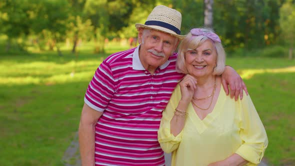 Active Senior Grandfather Pensioner Walking to Stylish Grandmother and Making a Kiss in Summer Park