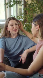 LGBT Women Sit Together in the Living Room Talk to Each Other Smiling and One of Them Touches Her