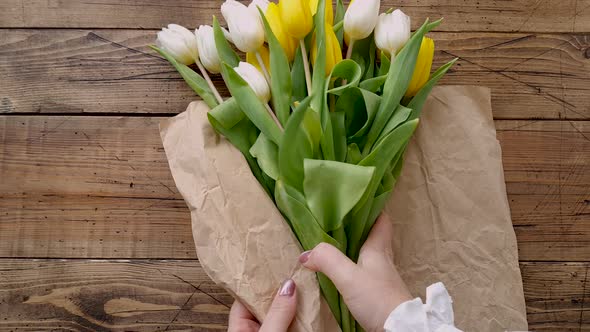 Making a bouquet from yellow and white tulips on a wooden table top view 