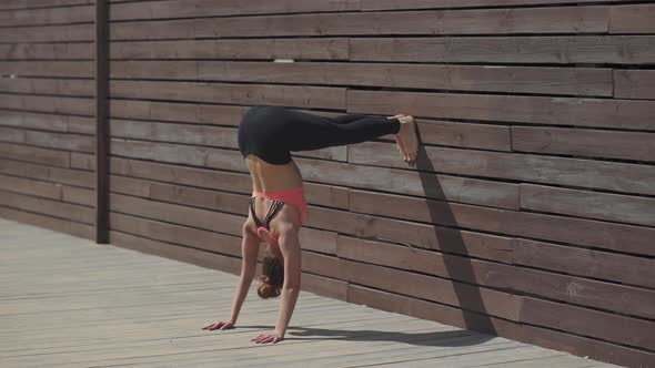 Woman Practicing Yoga Handstand Poses on Wall at Sunny Day