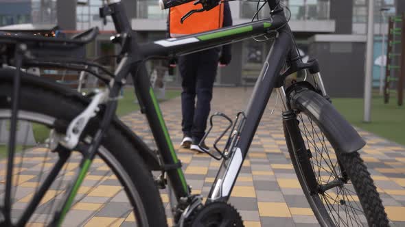 Courier Cyclist Walking to Entrance of Building