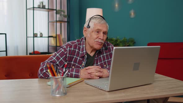 Senior Man Freelance Wear Headphone Make Video Call Talking Teaching at Laptop at Home Office