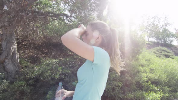 A young woman runner drinking water during her workout.