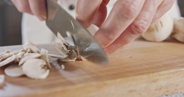 Close up of a chef knife slicing champignon mushrooms