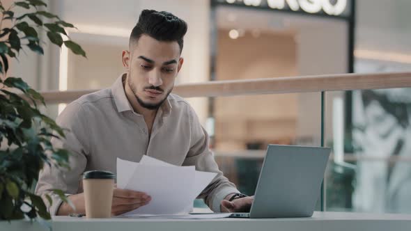 Serious Busy Multitasking Arabian Indian Businessman Checking Corporate Paperwork Sitting at Office