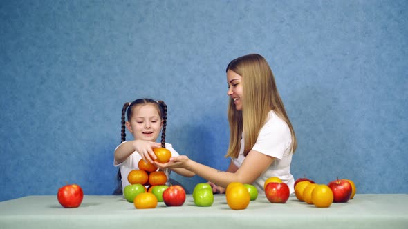 Happy little girl with fruits. Little girl playing with fruits sitting at the table