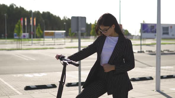 Business Woman Standing with Electric Scooter Wearing Black Suit