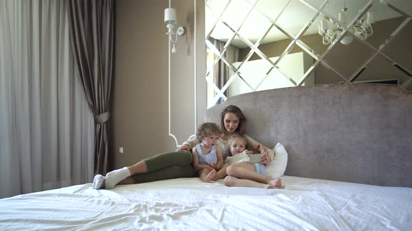 Family With Phone. Woman And Children Using Phone At Bedroom