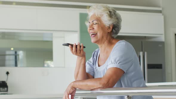 African american senior woman smiling while talking on smartphone at home