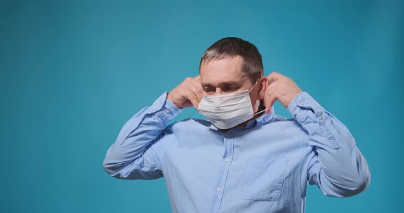 Handsome Serious Man Demonstrates Putting on White Face Mask