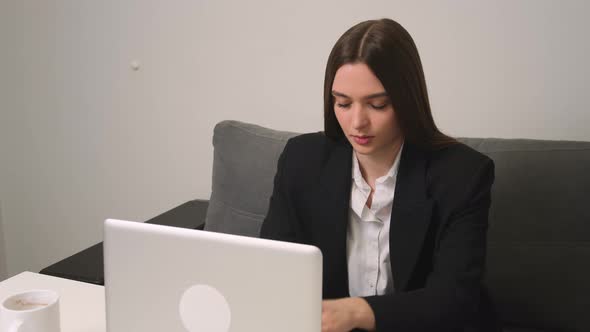 Pretty Young Woman Coughing While Using Laptop at Home Office