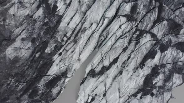 Aerial view over darkened, sooty glacier surface, in Iceland - overhead, drone shot