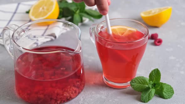 Mixing raspberry tea with lemon with spoon