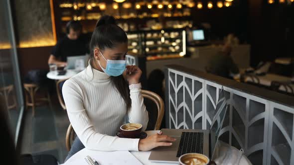 Pretty Woman Wearing Medical Face Mask Using Laptop to Work