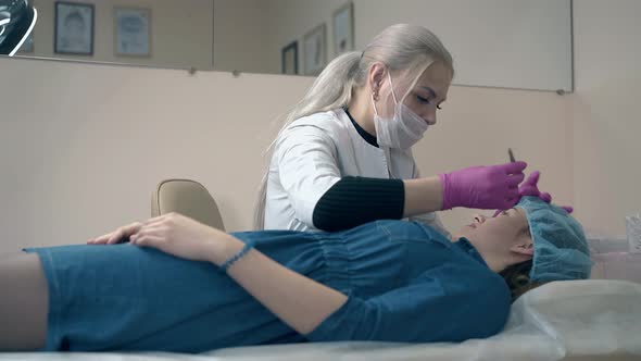 Woman Tweezes Eyebrows of Client with Tool in Clinic