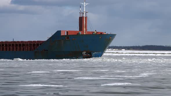 Cargo Ship Sailing Through Frozen Sea Ice in Winter