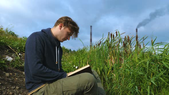 A Young Man Sits By the River and Reads a Book