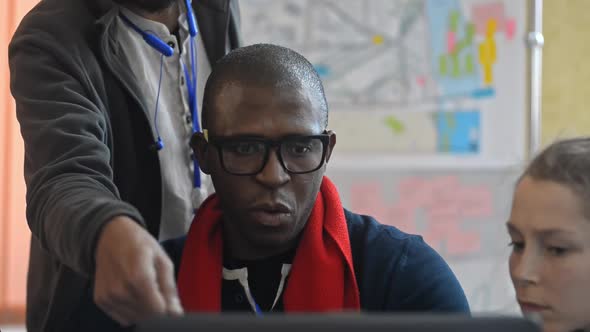 American African Man and Team Are Working on Blueprint at Table with Laptop at University Irrl