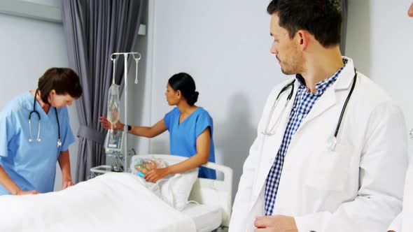 Two doctors discussing over medical report while nurse examining a patient