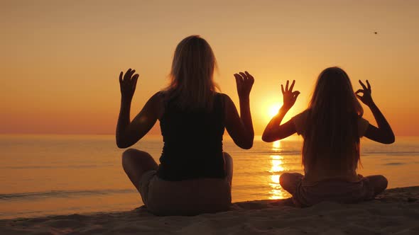 A Young Mother with Her Daughter Sitting on the Beach