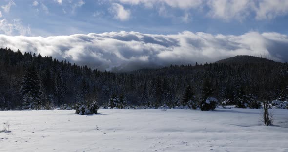 Time-lapse of clouds flowing over the mountain peak on a winter sunny day