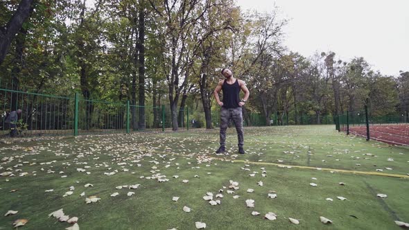 Muscular sportsman doing exercises in the open air. 