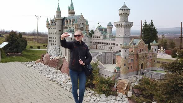 Woman Takes a Selfie Near a Miniature Model of the Old Castle Neuschwanstein, Germany. Park of