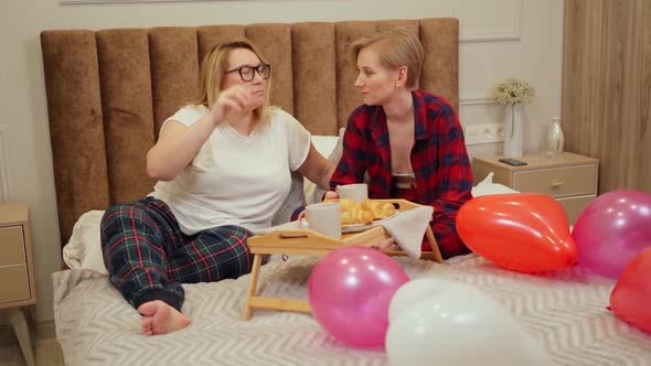 Lgbt Married Couple Have Breakfast in Bed on a Side Table Heartshaped Balloons Lie Around