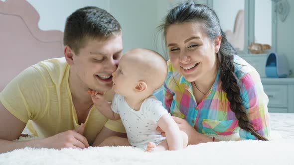 Happy Family - Mother, Father and Baby on the Bed