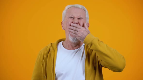 Sleepy Aged Man Yawning on Camera Against Orange Background, Insomnia Problem