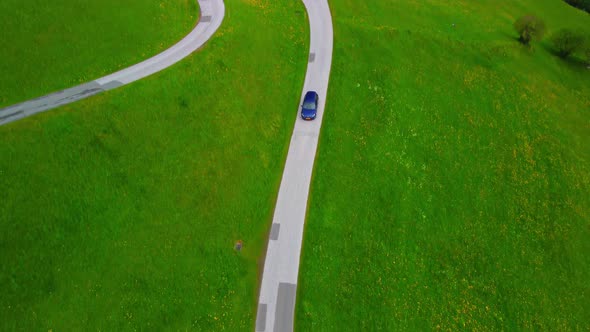 Volkswagen golf driving on an alpine road surrounded by green fields in Austria.