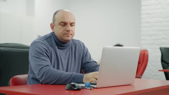 Mature Programmer Man Is Working on Laptop in the Office