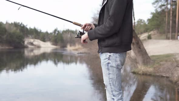 The guy in his free time catches a predatory fish on spinning from the shore. Fishing as a hobby.