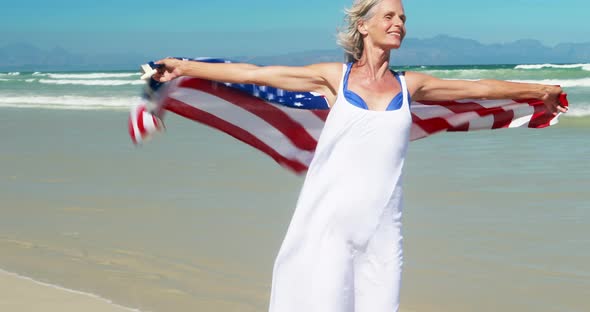 Senior woman with american flag at the beach