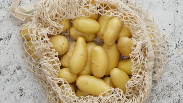 Young Fresh Potatoes in a Ecological Zero-waste Net Bag Placed on White Scratched Background