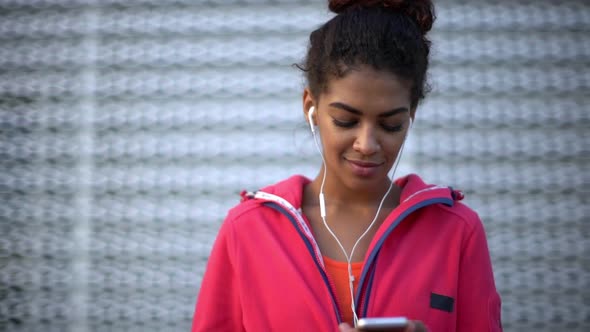 Picture of Attractive Mixedrace Woman with Tied Dark Hair Wearing Sport Clothes Enjoying Music Via