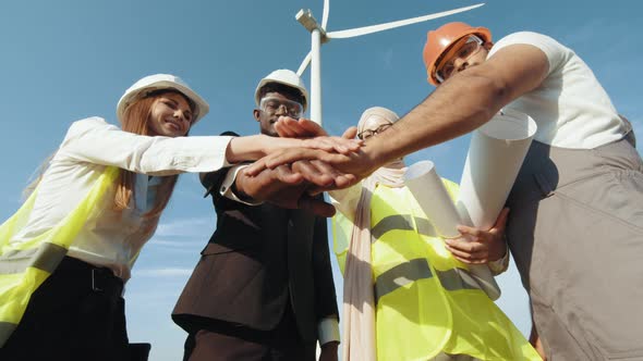 Group of Four Multicultural Partners Stacking Hands Together and Smiling on