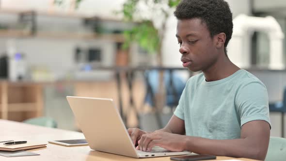 Serious Young African Man with Laptop Looking at Camera